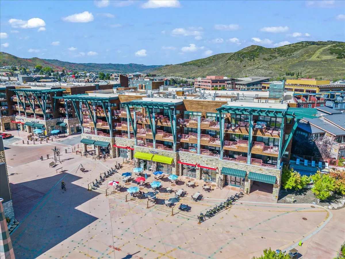 Multi-story building featuring stone and wood-look siding, individual balconies, and ground-level commercial spaces with awnings