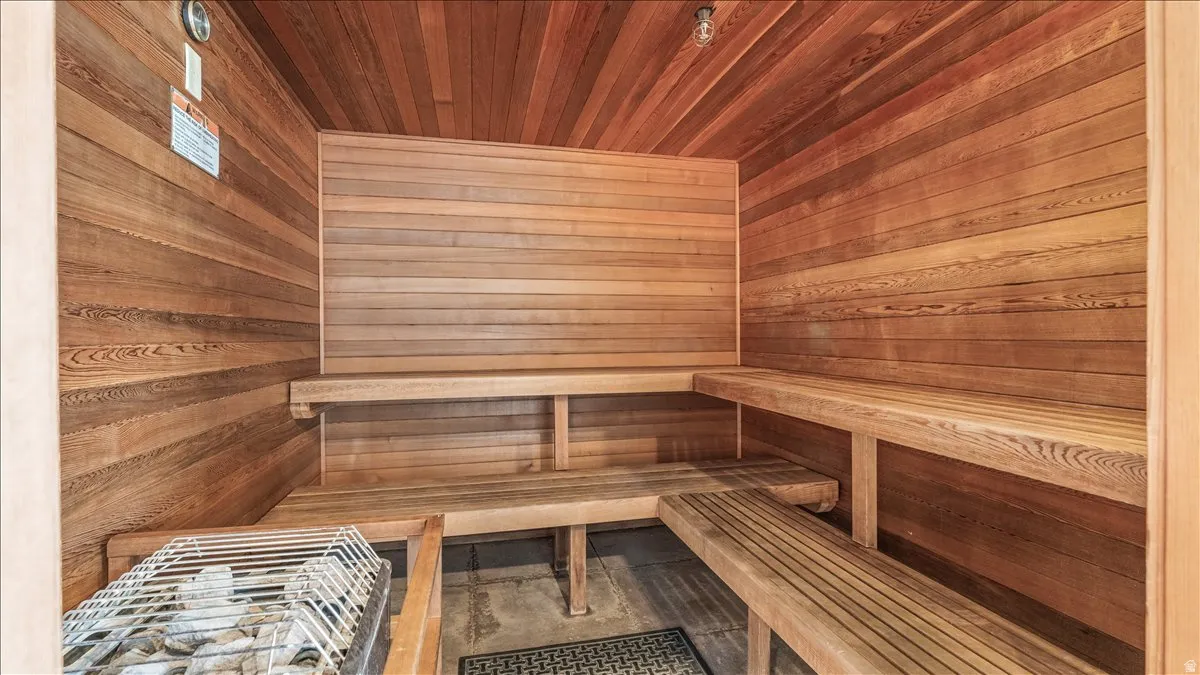 Interior sauna featuring slatted wood benches, wood-paneled walls, and a stone-filled heater unit