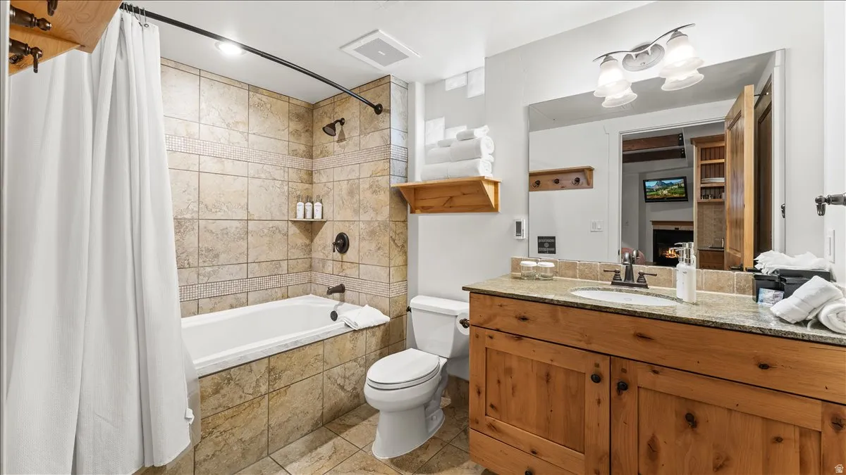 Bathroom featuring a built-in bathtub with subway tile surround, a wood-finish vanity with a granite countertop, and a large wall-mounted mirror