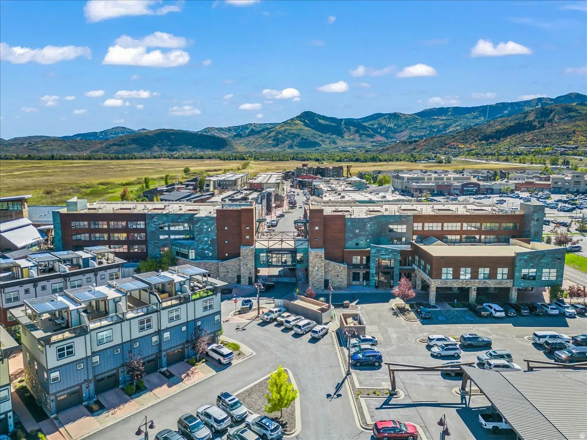 Expansive aerial view showcasing multiple commercial buildings with varied facades, a residential complex featuring rooftop access, and abundant surface parking