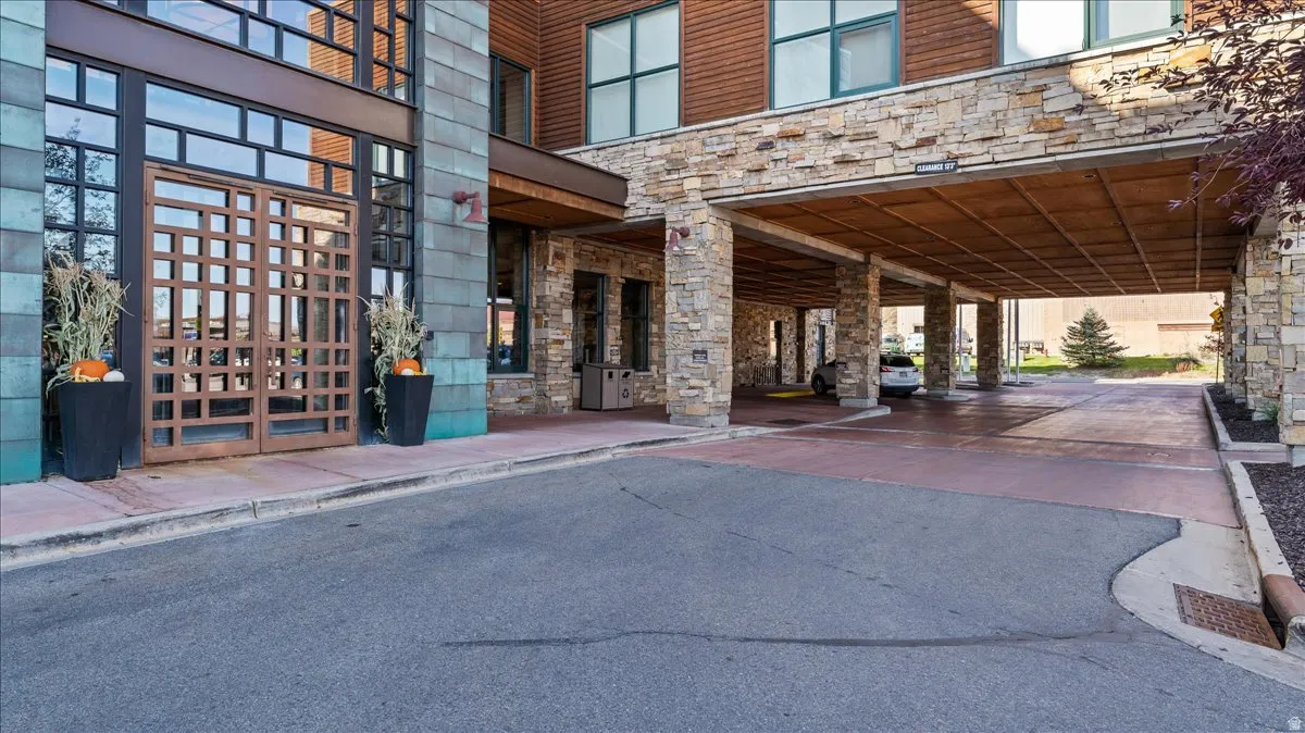 Exterior featuring a stone facade, a multi-pane glass entry, and a covered drive-through portico with stone columns