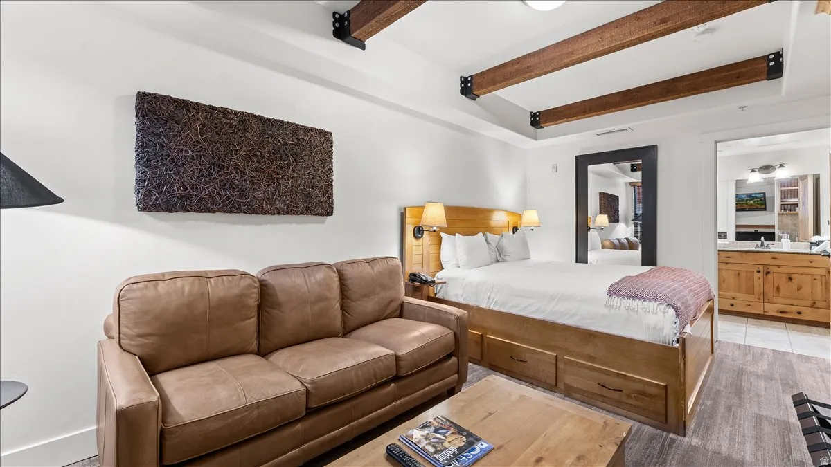 Living area featuring exposed ceiling beams, wood-finish flooring, and a built-in bed frame with storage drawers