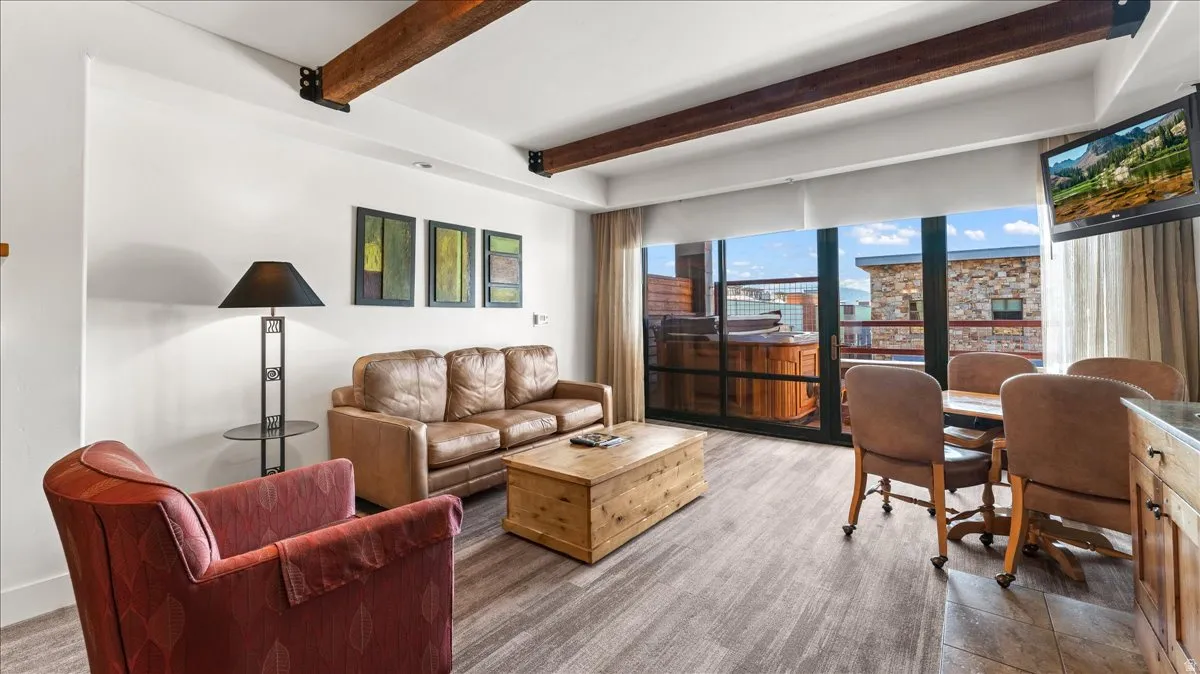 Open-concept living area featuring wood-finish flooring and exposed ceiling beams