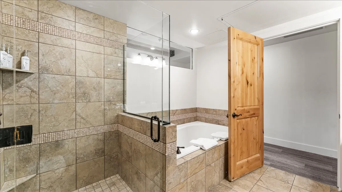 Tiled shower enclosure featuring a glass partition, integrated shelving, and a mosaic accent band