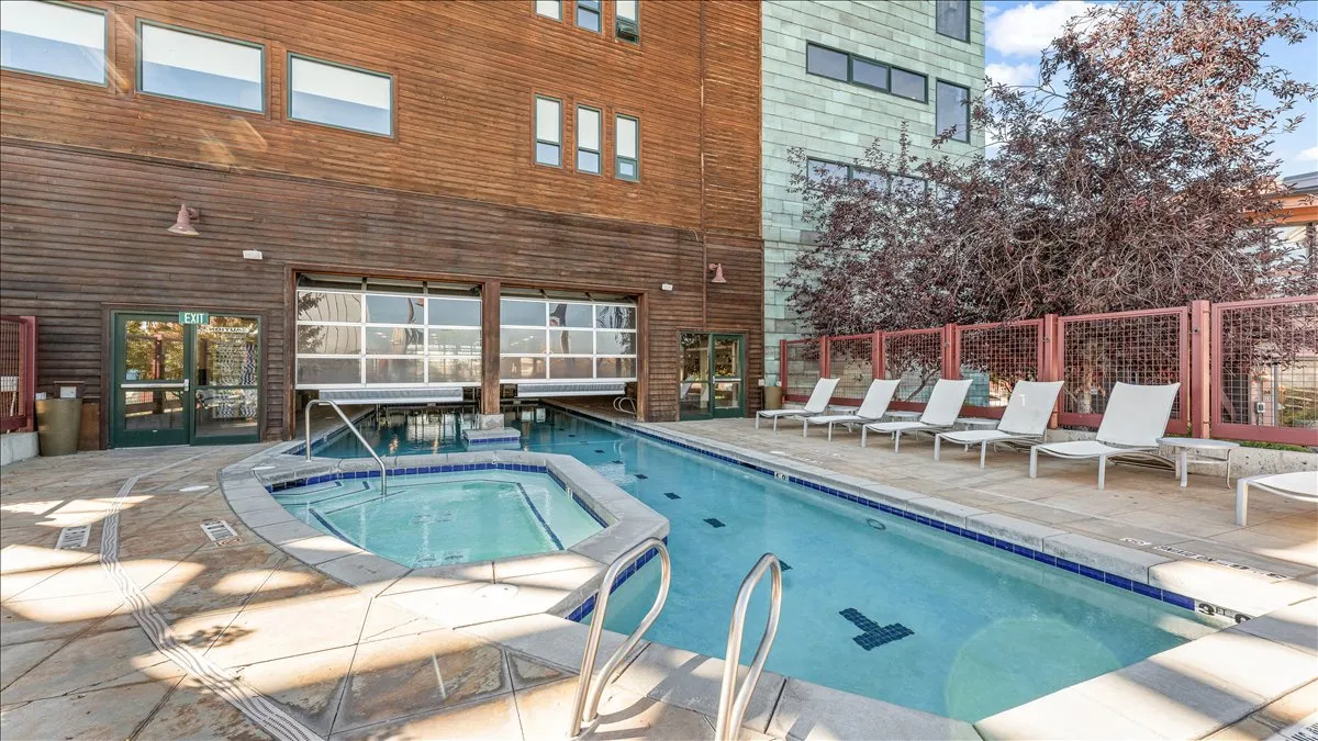 Outdoor aquatic area featuring a swimming pool and integrated spa, surrounded by stone-look decking