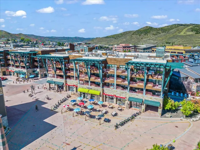 Multi-story building featuring stone and wood-look siding, individual balconies, and ground-level commercial spaces with awnings