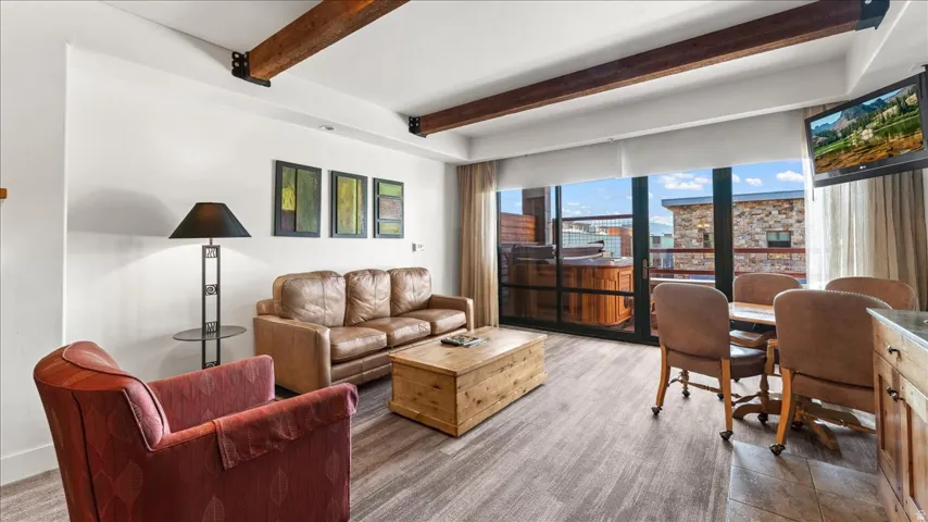 Open-concept living area featuring wood-finish flooring and exposed ceiling beams