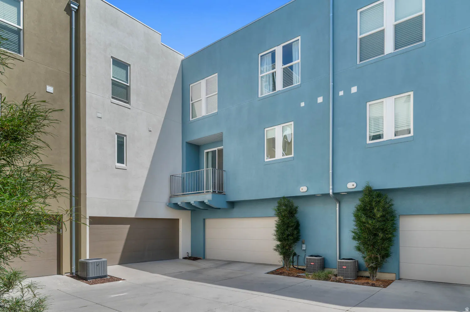 Modern multi-story facade featuring varied stucco finishes and multiple garage entrances
