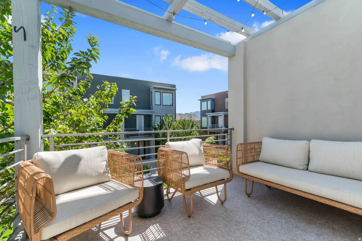 Open-air balcony featuring a wood pergola with string lighting