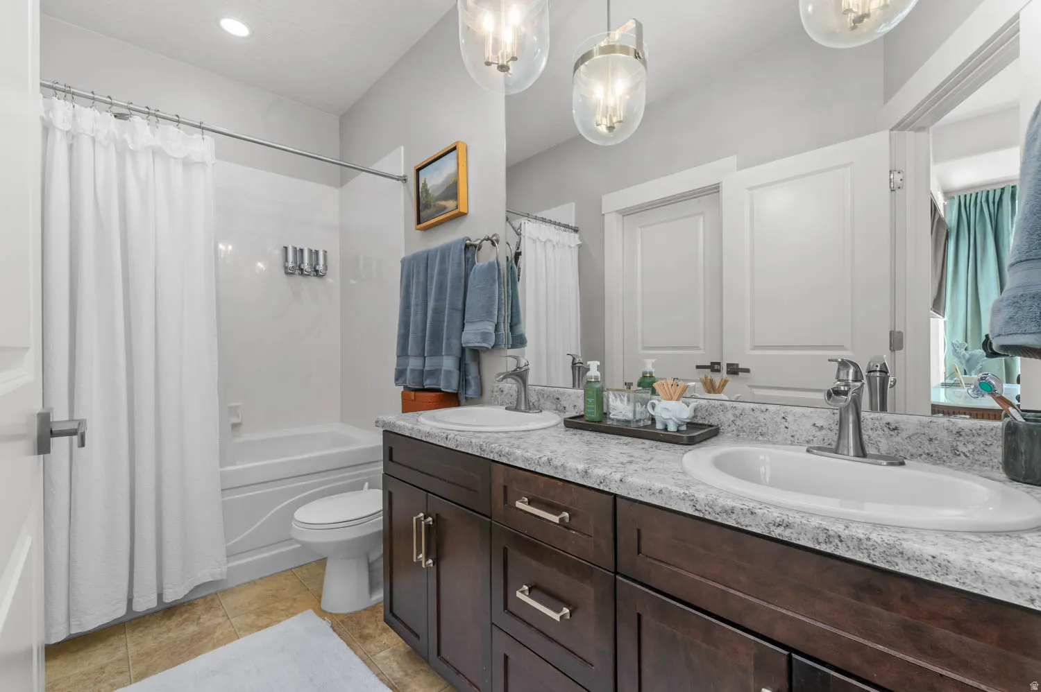 Bathroom featuring a dual vanity with a speckled countertop, undermount sinks, and wood-finish cabinetry