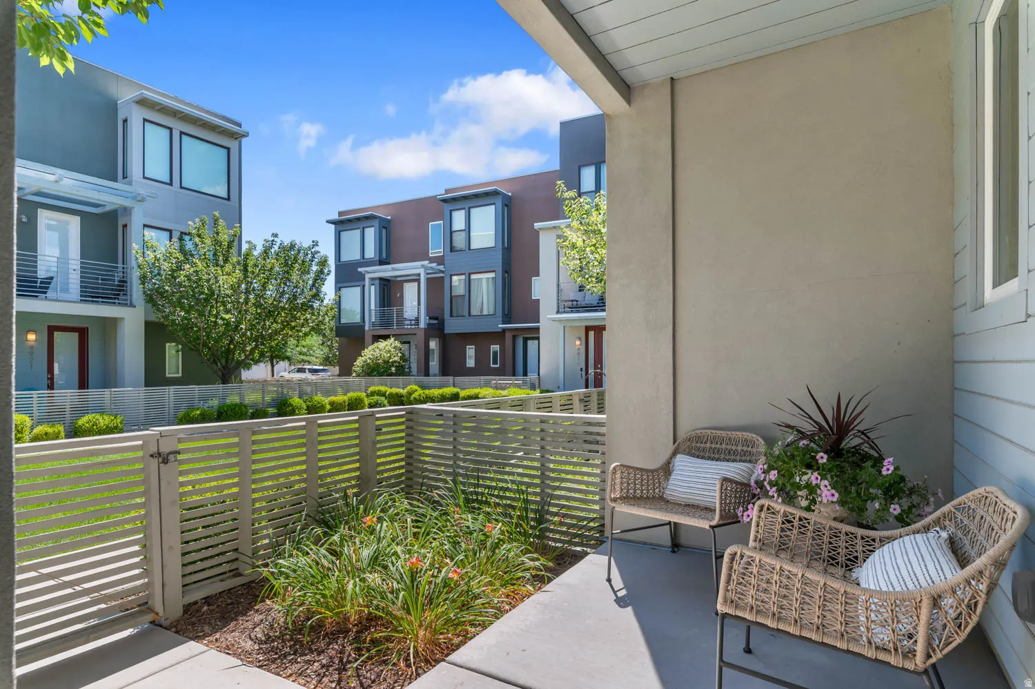 Covered outdoor patio with concrete flooring, stucco wall, and horizontal slat fencing