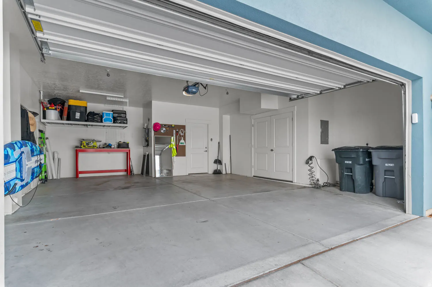 Spacious garage featuring a concrete floor, overhead door, and interior access door