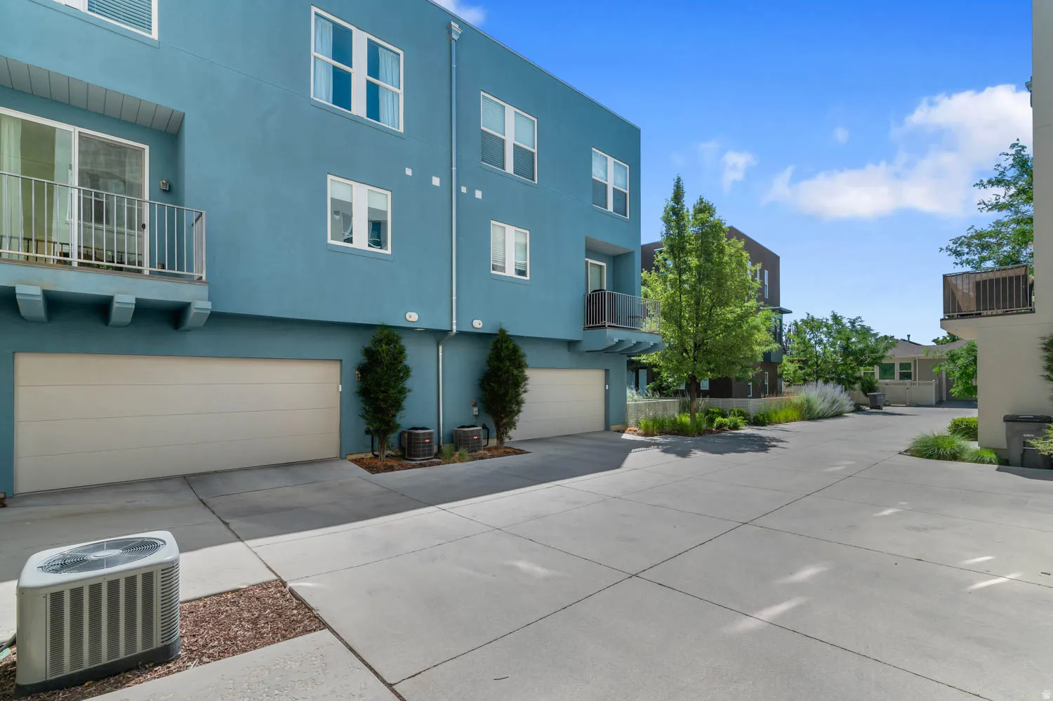 Modern architectural design featuring a bold teal exterior, multiple windows, and a private balcony with white railing