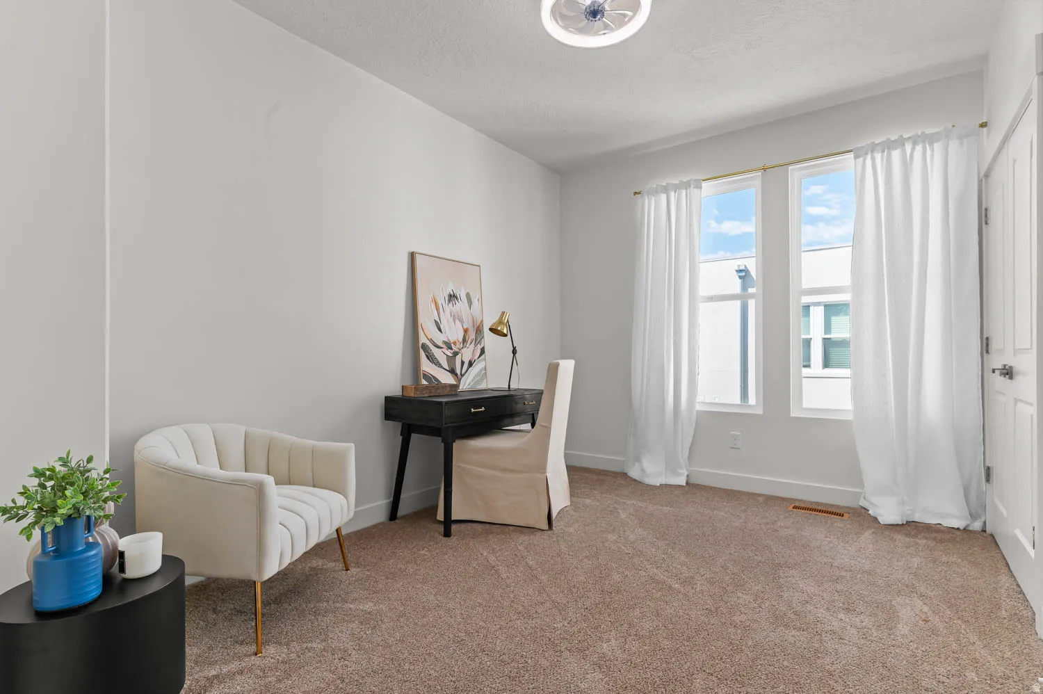 Carpeted room featuring multiple windows with white window treatments, white painted walls, and a ceiling-mounted light fixture