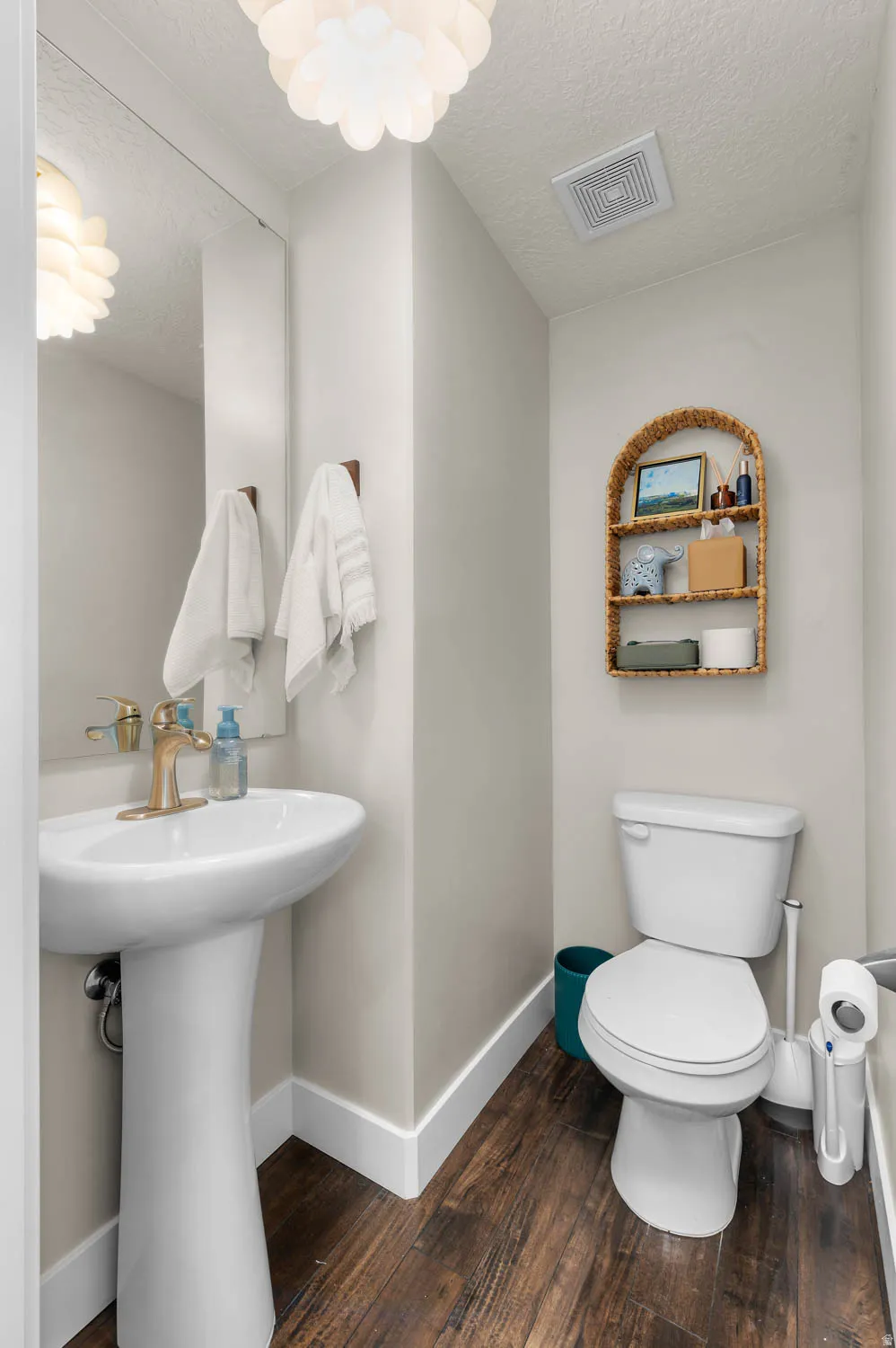 Pedestal sink with brass-finish faucet, full-height mirror, and wood-finish flooring