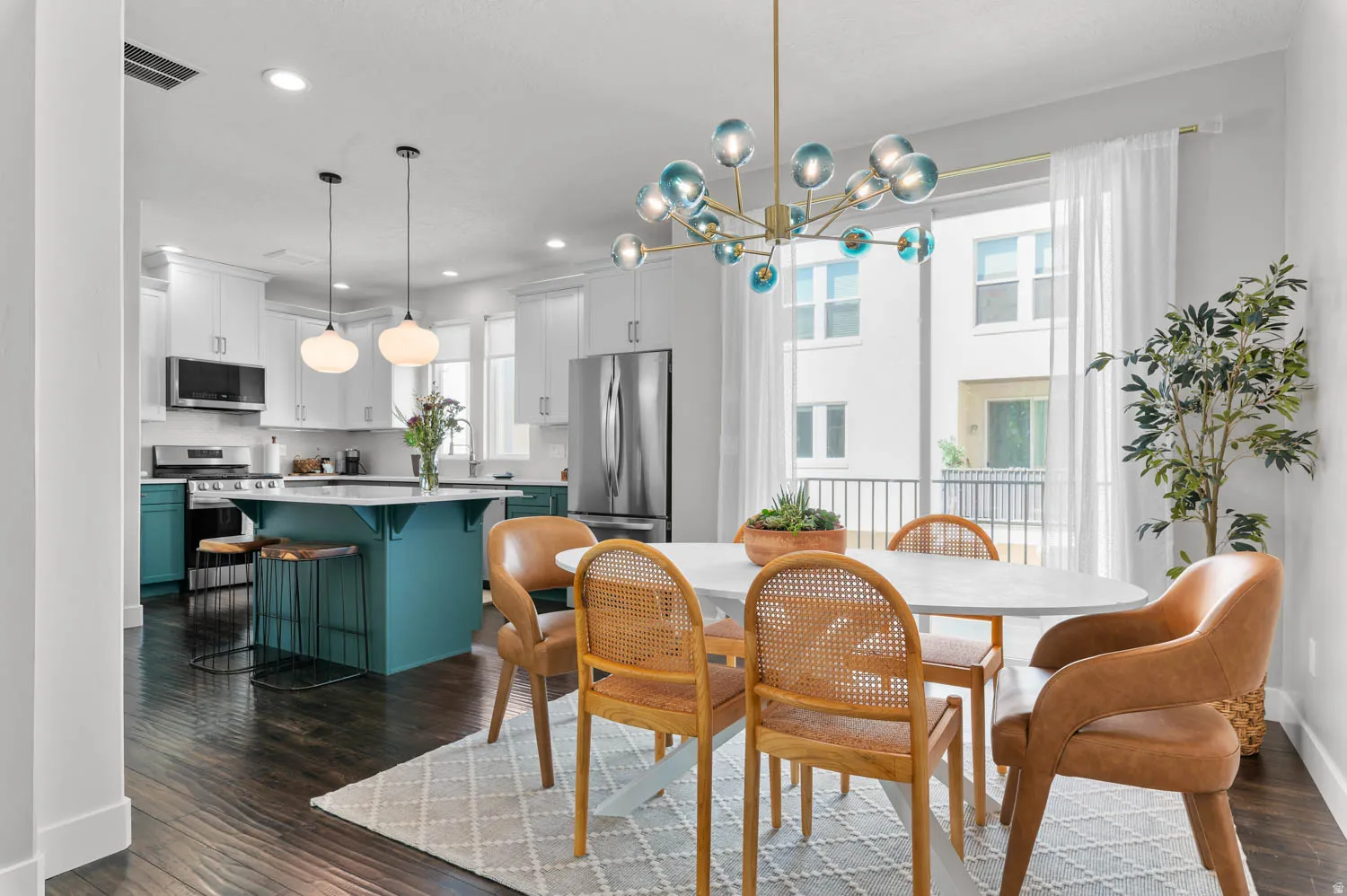 Open-concept kitchen and dining area featuring dark wood-finish flooring, a contemporary chandelier, and a kitchen island with seating