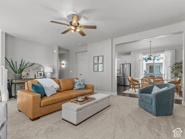Spacious living area featuring neutral carpeting, a ceiling fan, and an open doorway to a dining space