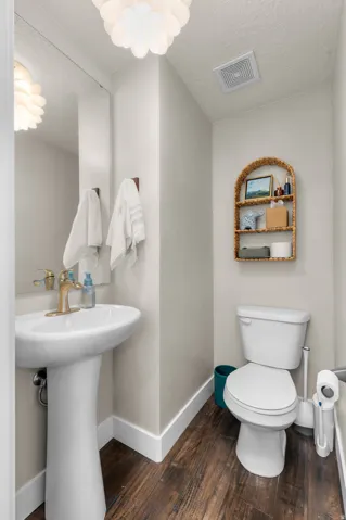 Pedestal sink with brass-finish faucet, full-height mirror, and wood-finish flooring