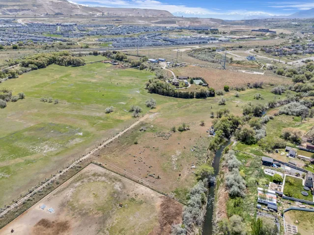 Expansive acreage featuring a natural waterway, diverse tree cover, open fields, and distant mountain backdrops