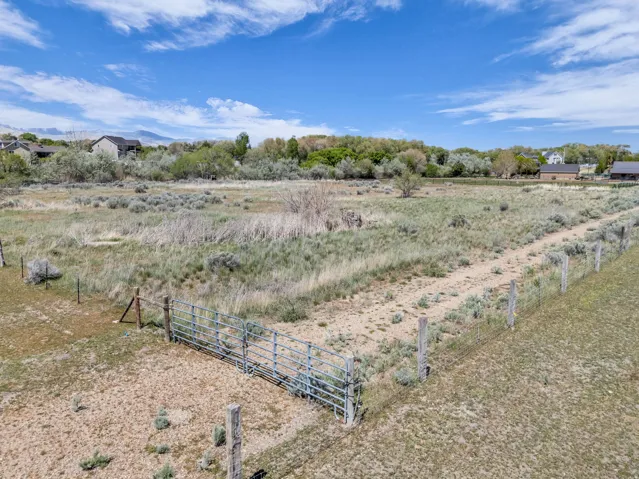 Expansive undeveloped land featuring a metal gate, perimeter fencing, and a dirt path
