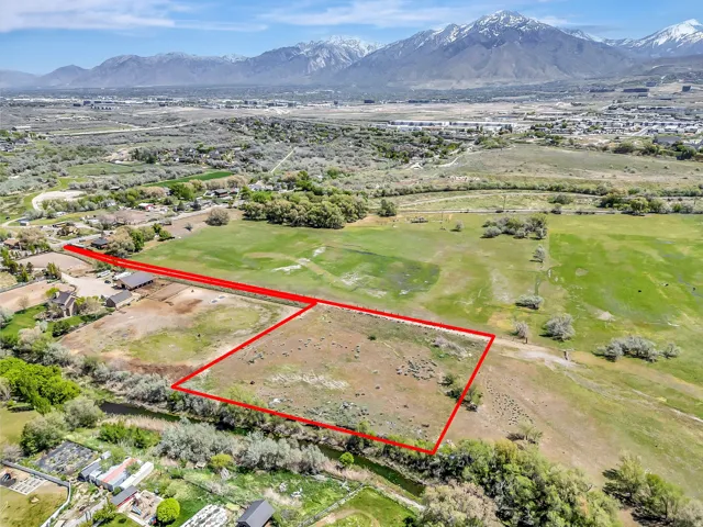 Expansive land parcel with surrounding green fields and mountainous backdrop