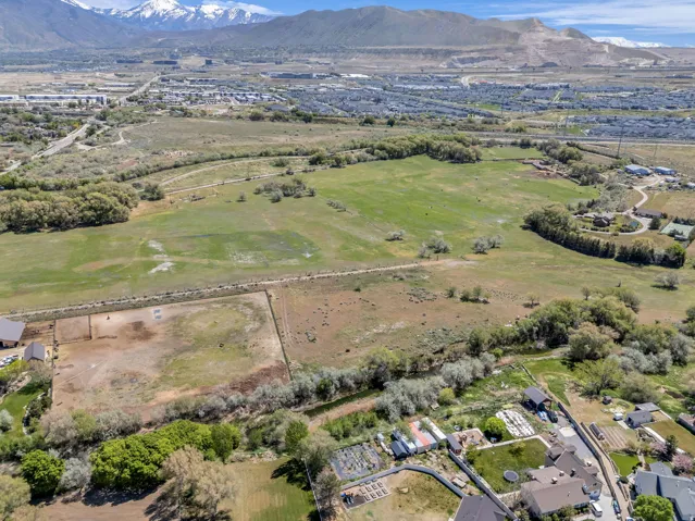 Expansive rural landscape featuring a large grassy field, distant snow-capped mountains, and a distinct equestrian arena