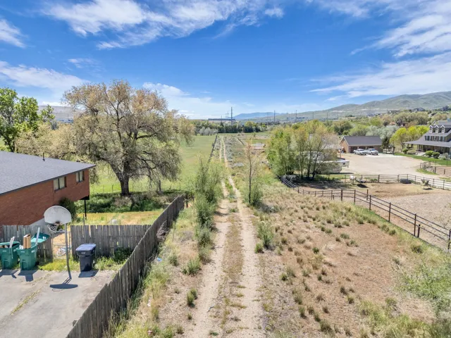 Expansive undeveloped land featuring a dirt path, mature trees, and mountainous terrain in the distance