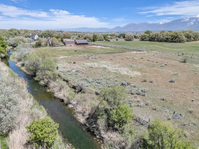 Expansive property featuring a tranquil stream, open fields, and distant mountain ranges