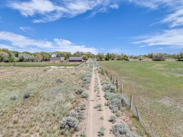 Extensive open fields featuring a dirt path, natural vegetation, and a rustic fence line