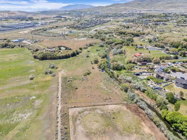 Expansive land parcel featuring a natural water channel, established foliage, and distant mountain backdrops