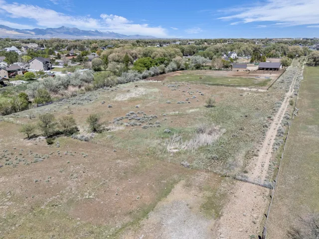 Expansive parcel featuring a natural landscape, a dirt track, and mature trees lining a portion of the property perimeter