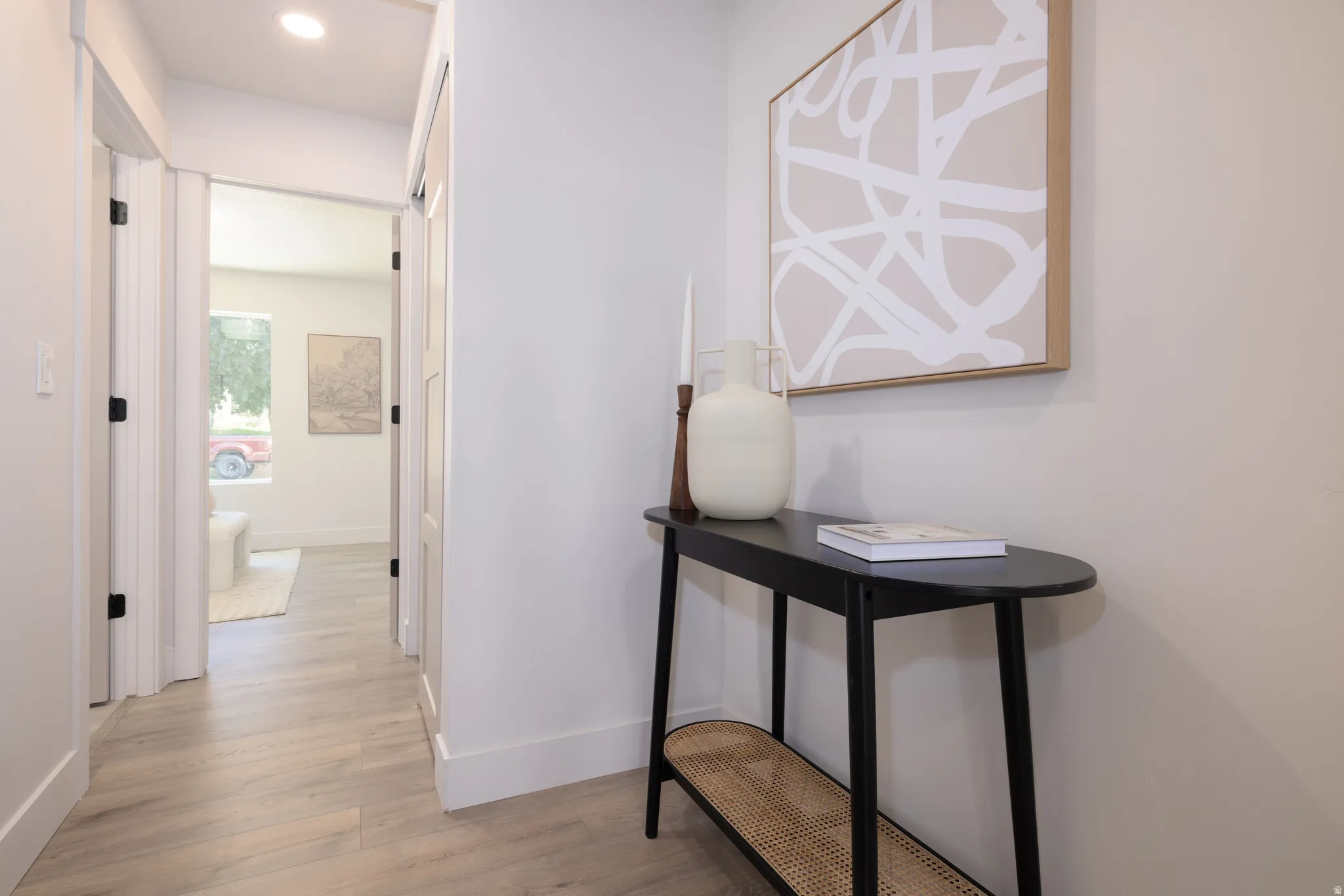 Hallway featuring wood-finish flooring, recessed lighting, white trim, and doors with black hardware