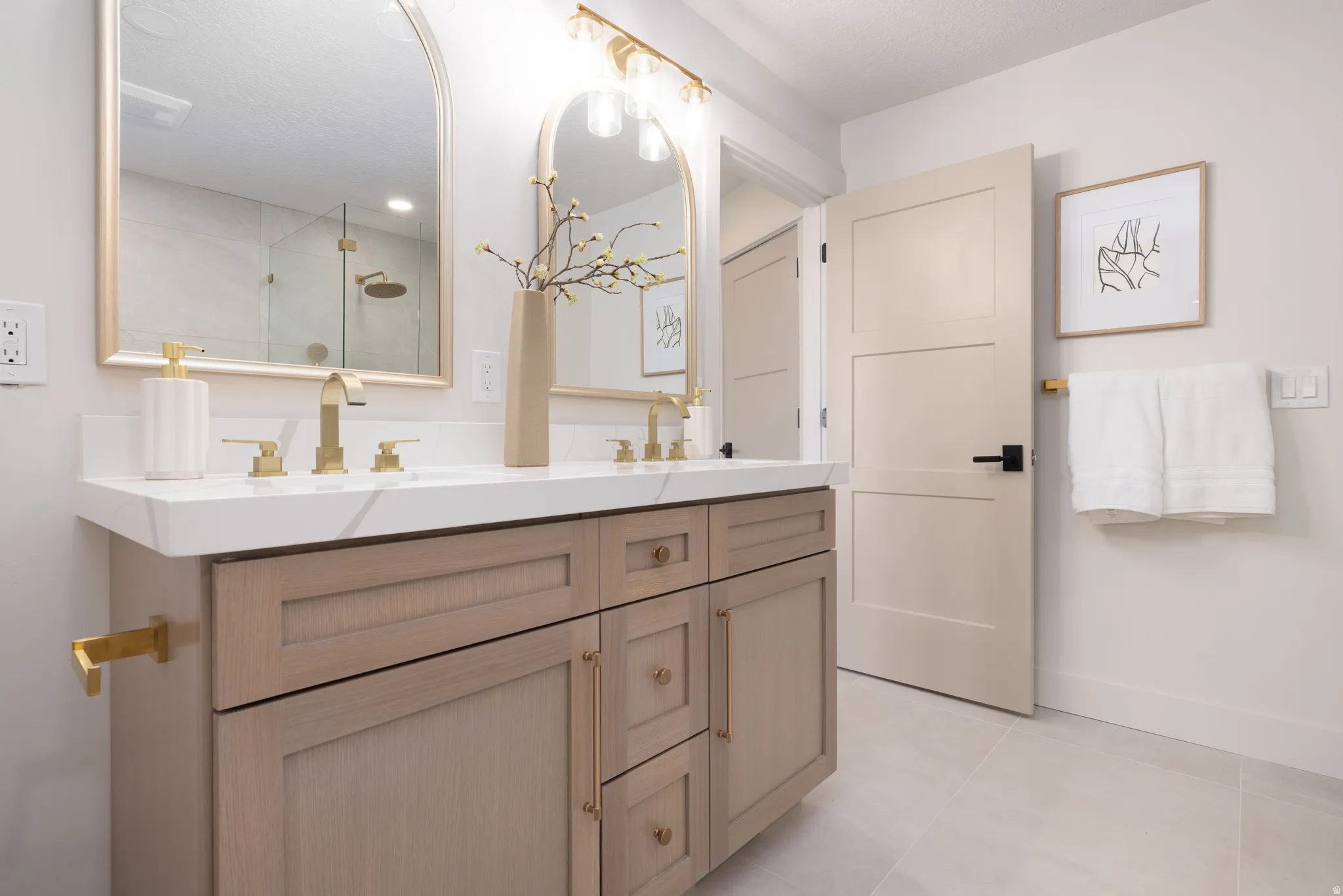 Double vanity featuring wood-finish cabinetry, white countertop, and gold-tone fixtures