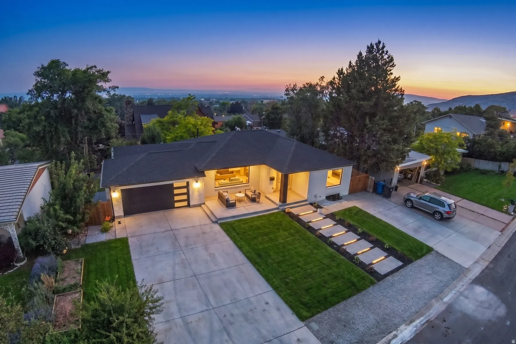 Modern single-story residence with a dark shingle roof, light-toned exterior, and an attached two-car garage