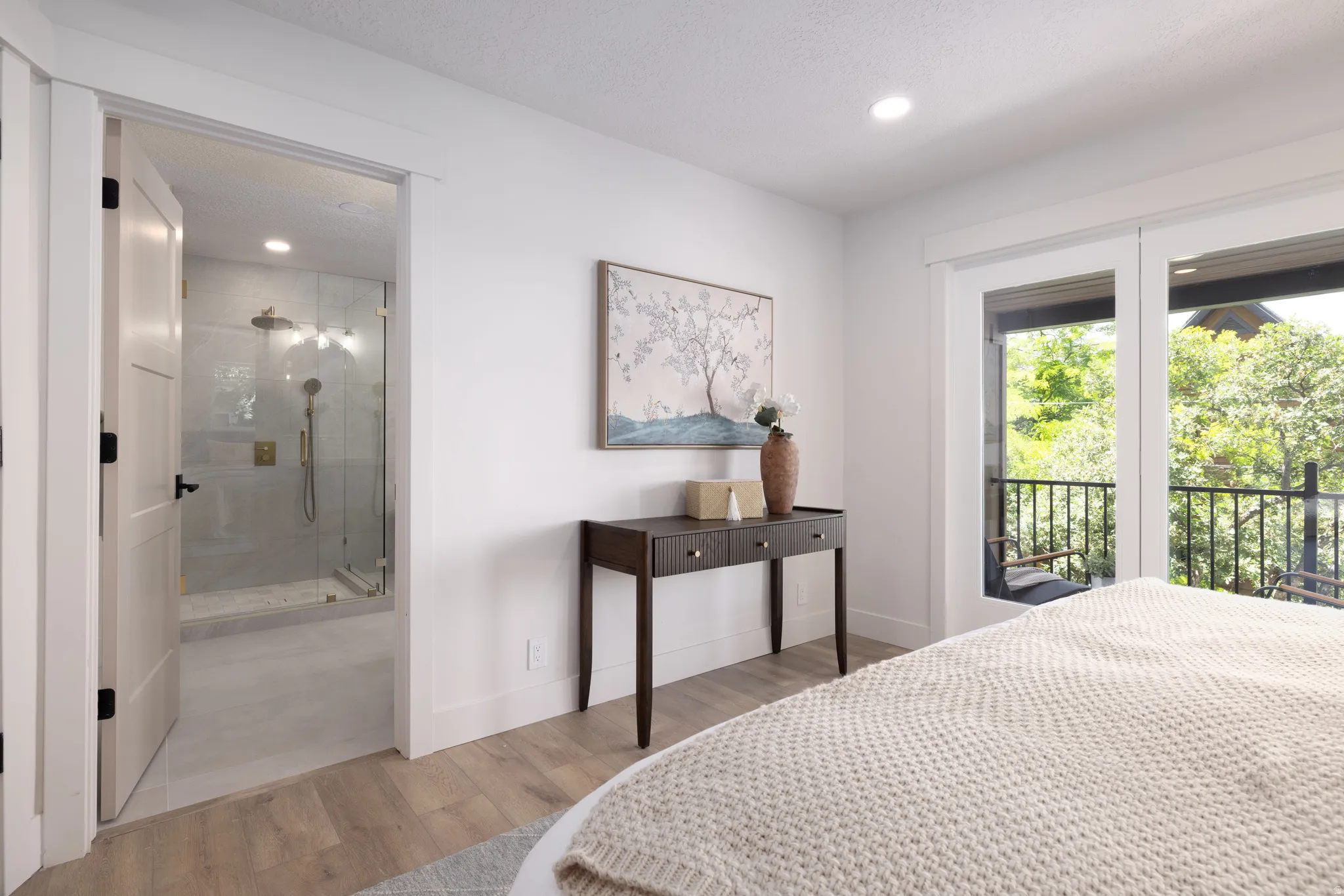 Spacious room featuring wood-finish flooring, recessed lighting, and a private balcony with black metal railings
