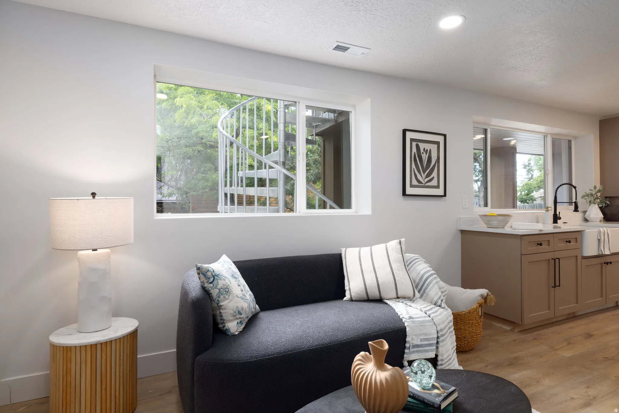 Living area with recessed lighting, wood-finish flooring, and a large window overlooking a spiral staircase