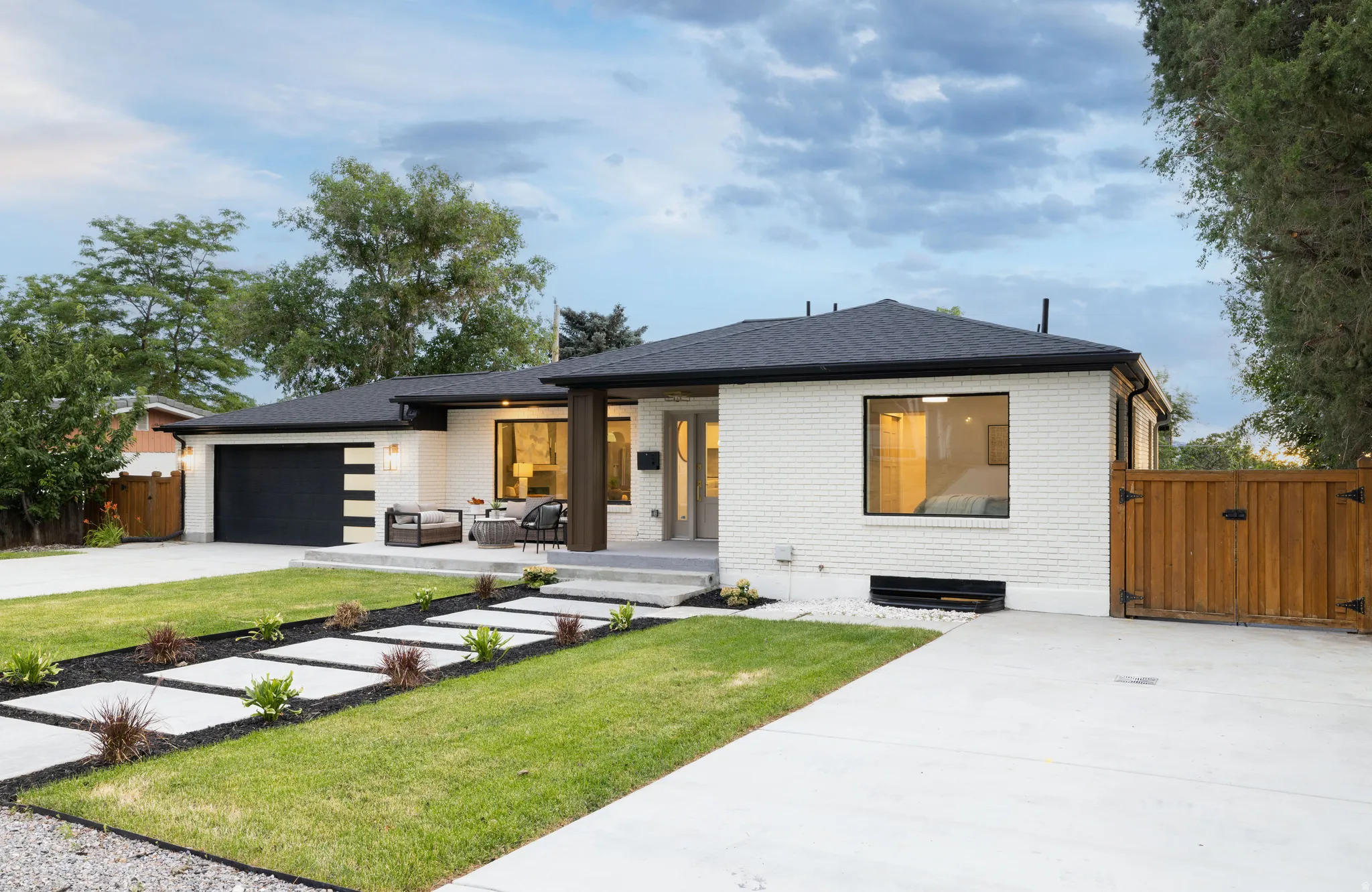 Contemporary ranch-style exterior featuring white brick siding and a dark shingled roof