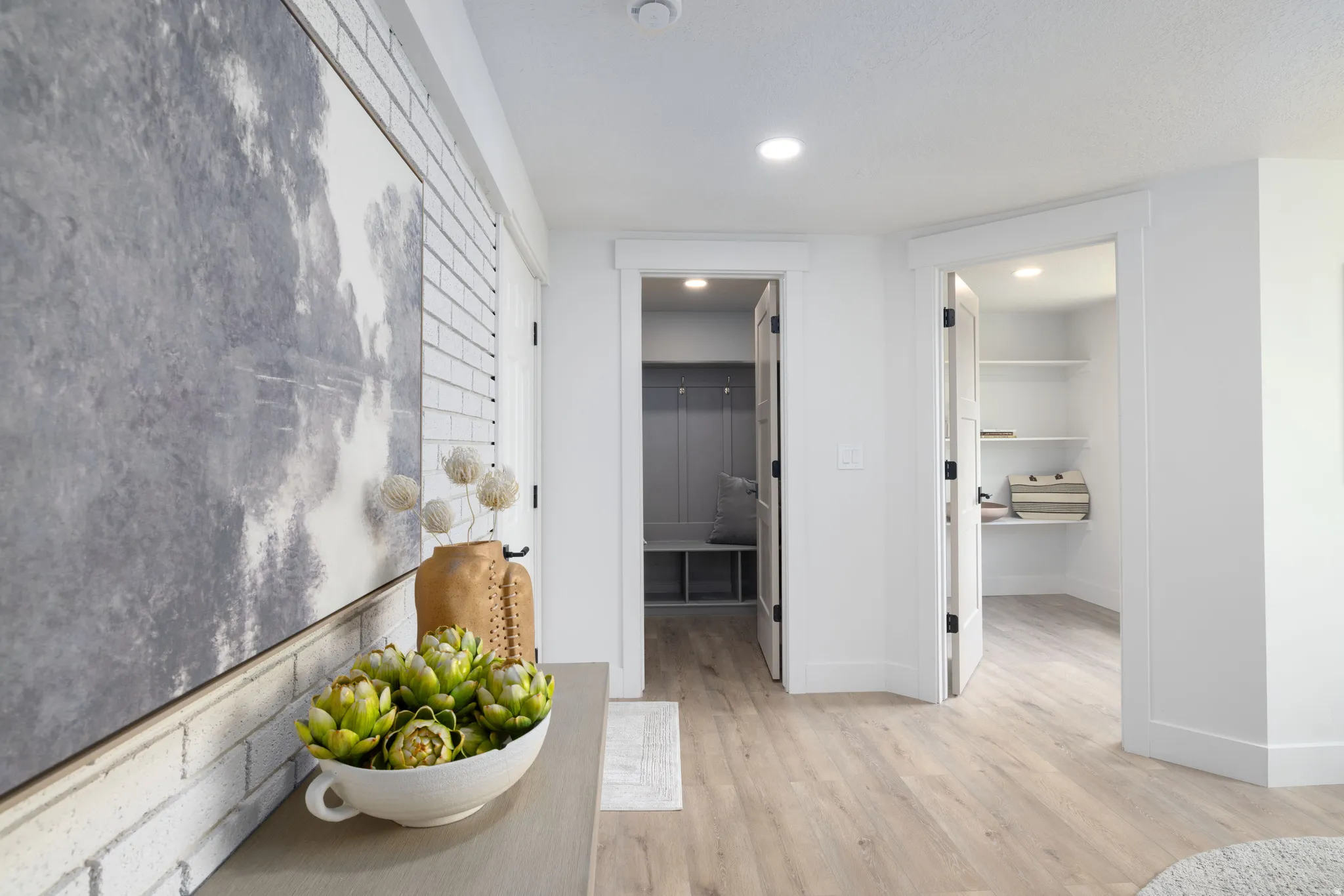 Hallway featuring light wood-finish flooring, white trim, recessed lighting, and a white brick-style accent wall