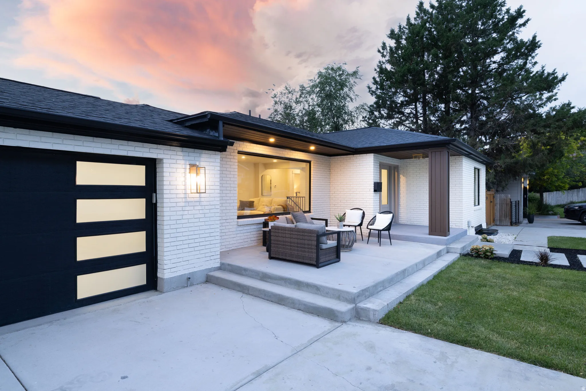 Modern exterior featuring white brick siding, a dark asphalt shingle roof, and a black garage door with horizontal frosted panels
