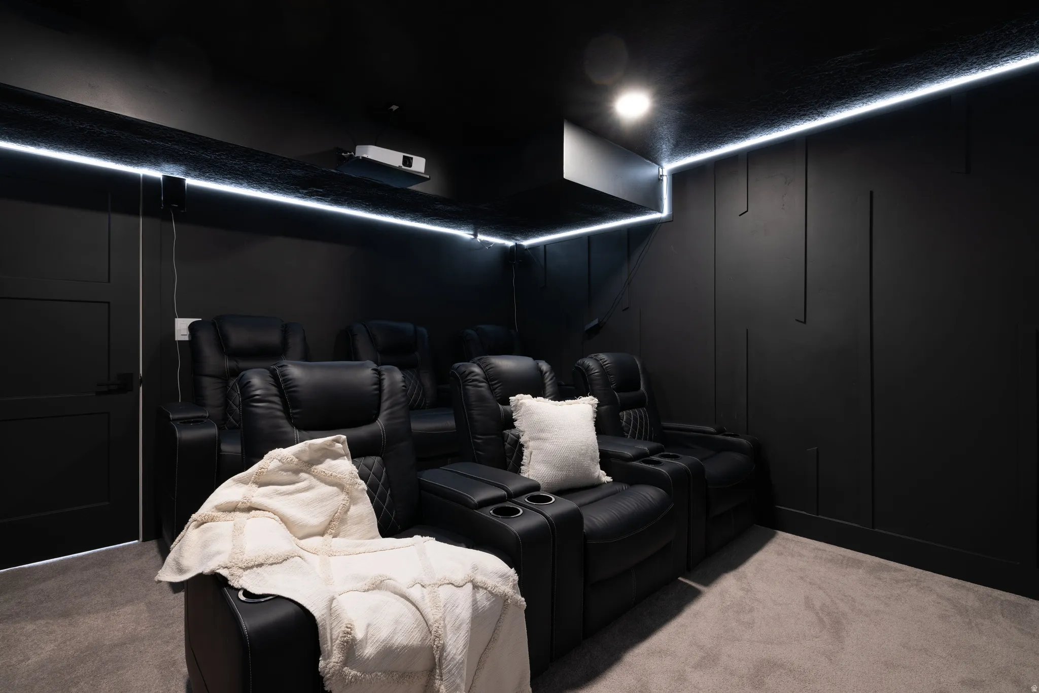 Dedicated media room featuring perimeter LED strip lighting, recessed ceiling lighting, and dark wall paneling