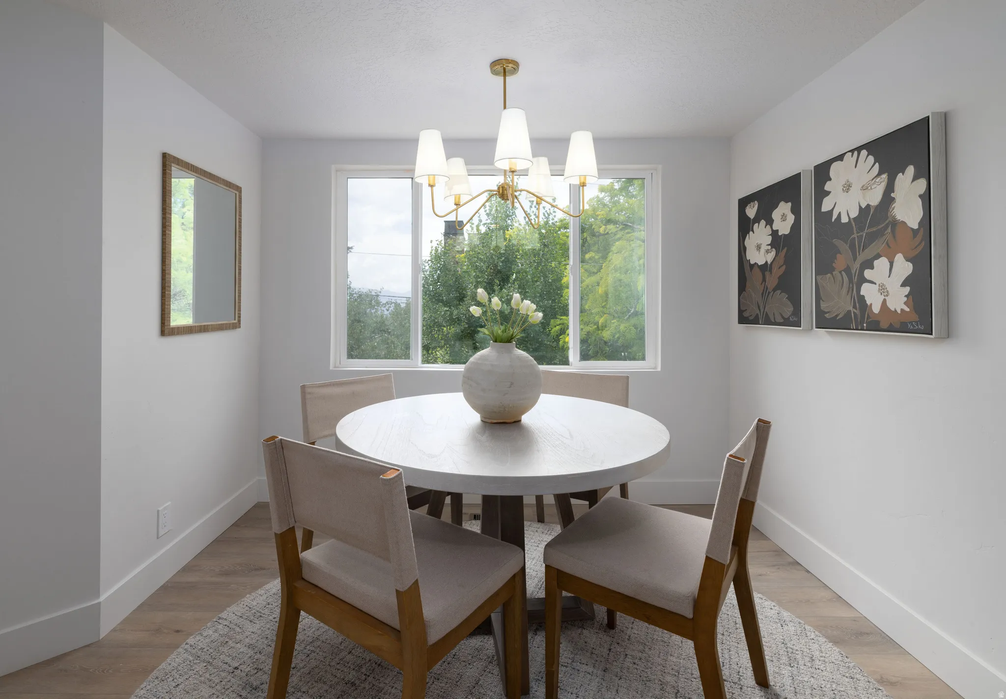Dedicated dining area featuring wood-finish flooring, white baseboards, and a contemporary chandelier