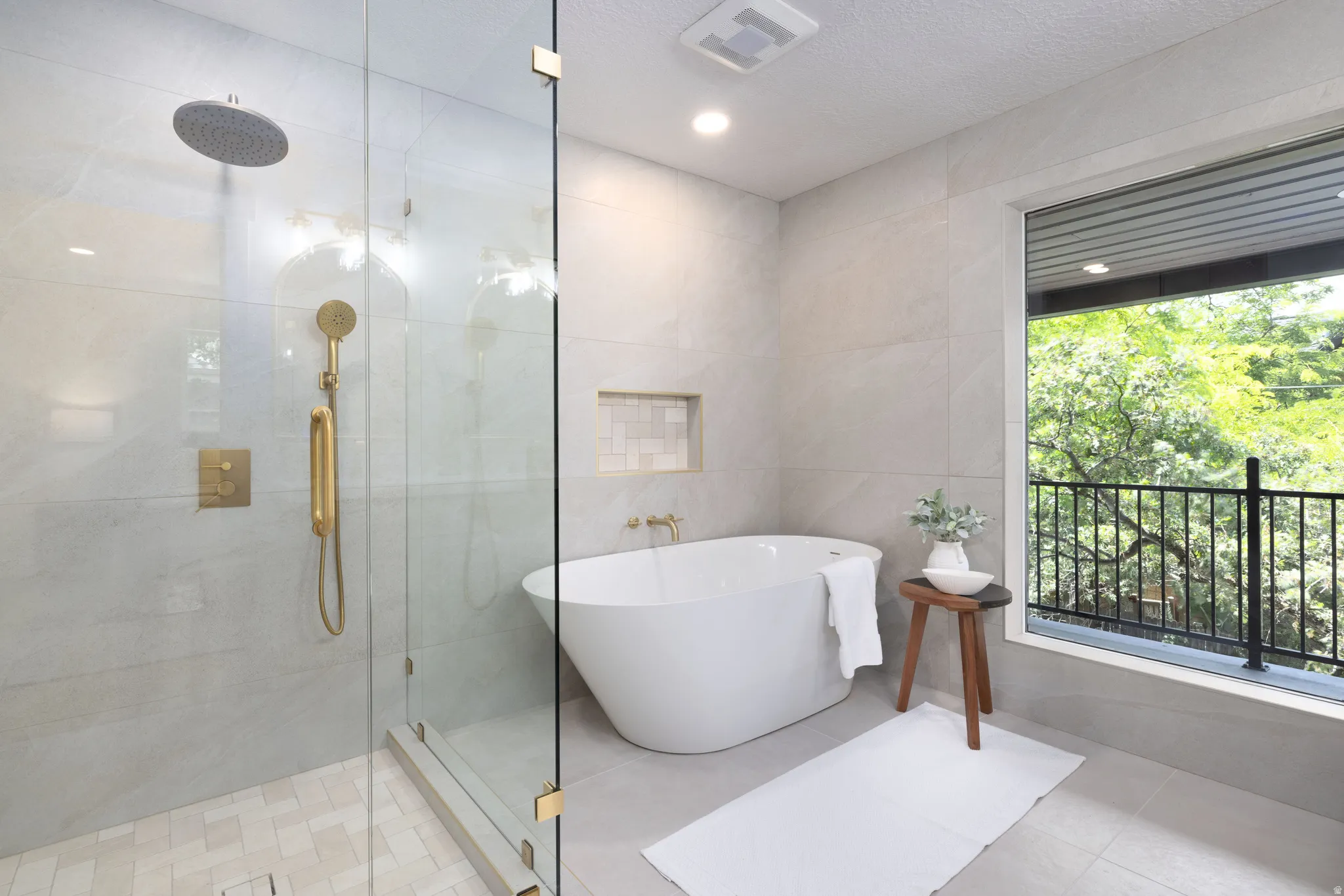 Contemporary bathroom featuring a freestanding soaking tub, a frameless glass shower enclosure with gold-tone fixtures, and a recessed tiled niche