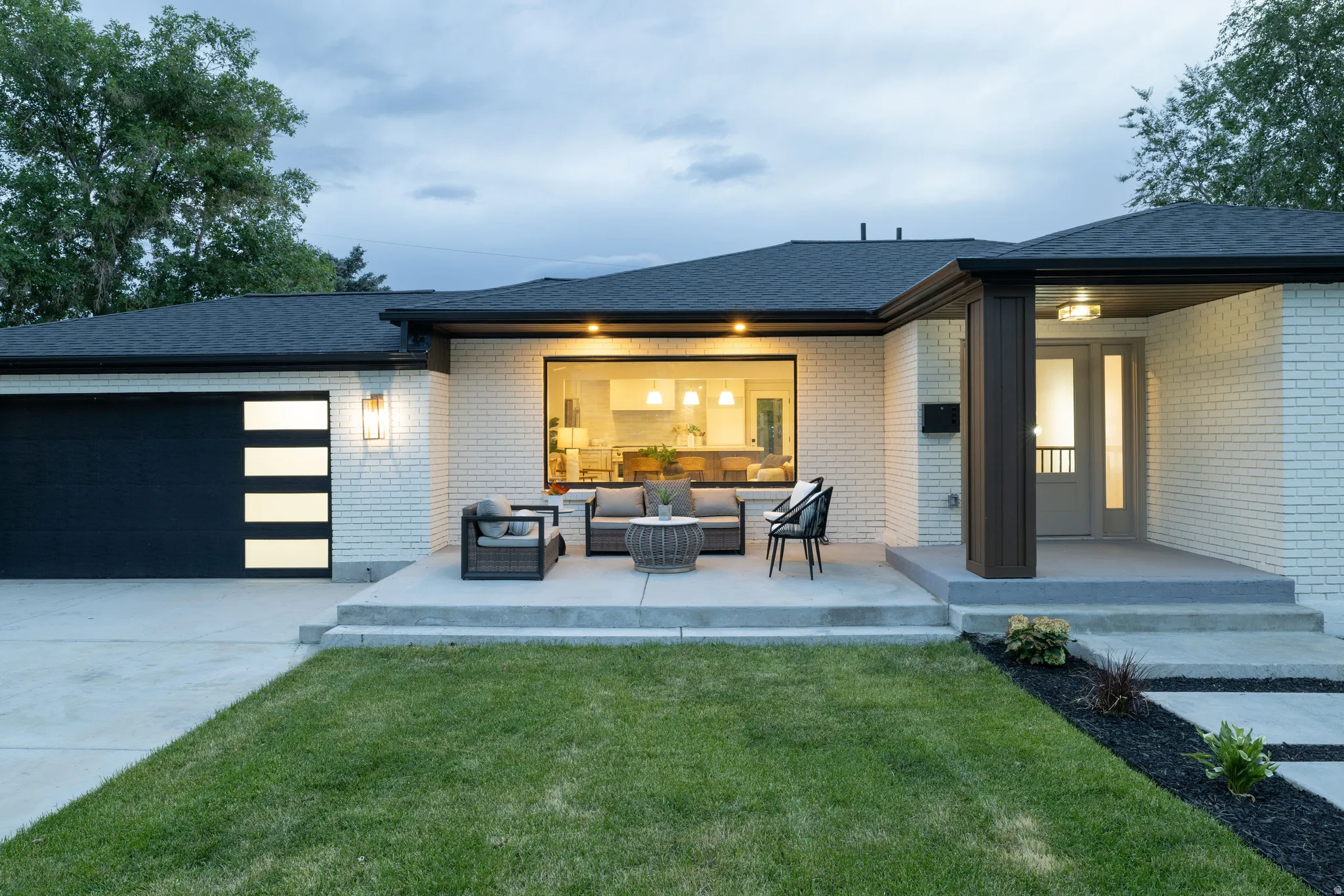 White brick facade featuring a dark asphalt shingle roof and a modern garage door with translucent panels