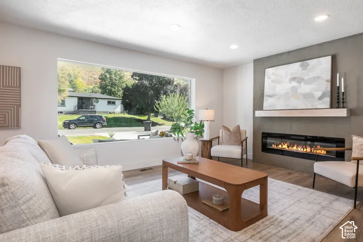 Recessed lighting, a linear electric fireplace with a floating mantel, and wood-finish flooring