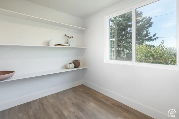White walls with integrated shelving, wood-finish flooring, and a large multi-pane window