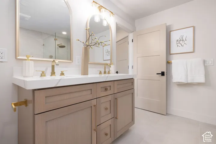 Double vanity featuring wood-finish cabinetry, white countertop, and gold-tone fixtures