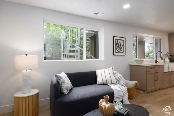 Living area with recessed lighting, wood-finish flooring, and a large window overlooking a spiral staircase