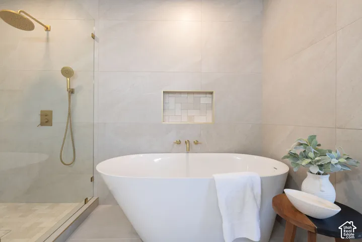 Modern bathroom featuring a freestanding soaking tub, glass-enclosed shower with gold-tone fixtures, and a recessed shower niche with decorative tile