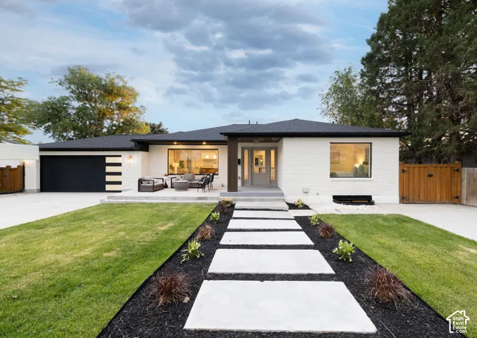 Contemporary single-story residence featuring a white brick exterior and a dark roof