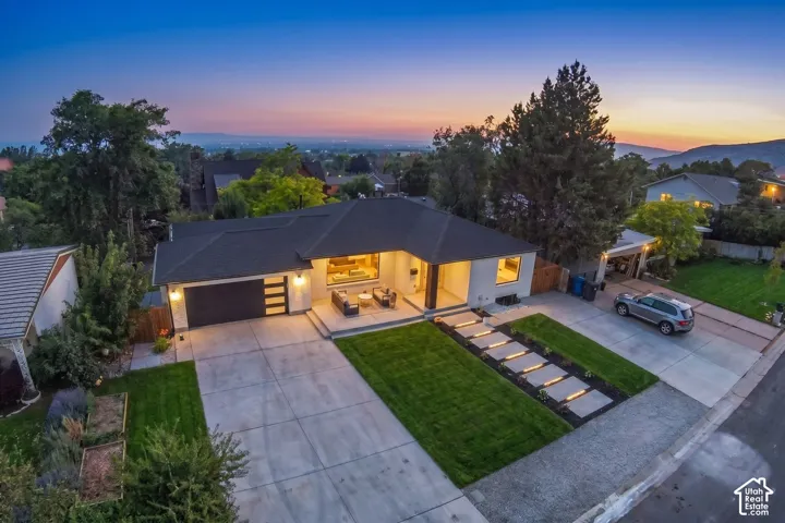 Modern single-story residence with a dark shingle roof, light-toned exterior, and an attached two-car garage